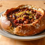 A golden, crusty sourdough bread bowl with a soft, fluffy interior, perfectly hollowed out and ready to be filled with a warm, comforting soup.